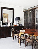 Elegant dining room with Chinese wooden partition and dark brown sideboard below large mirror; round, Chinese dining table in centre of room