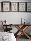 Framed drawings of insects on white wall above vintage table and chair
