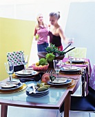 Gedeckter Tisch mit tropischen Blumen & Früchten, im Hintergrund Partygäste