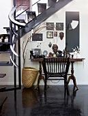 Console table, photo frames and African ornaments below interior staircase