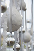 White and silver Christmas baubles hanging from ribbons (close-up)