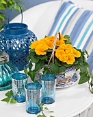 Orange primulas, blue glasses and lanterns on terrace table