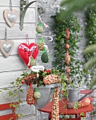 Bird food in red plastic nets, decorative hearts and flower arrangement