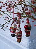 Weihnachtsmänner als Baumfiguren an roten Beerenzweigen aufgehängt