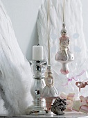 Angel Christmas tree baubles next to chrome candlestick in front of decorative angels' wings leaning on wall
