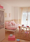 Charming girl's bedroom in pale pink with metal bed as sofa and teddy bear on child's table