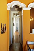 Ochre yellow walls with white-painted ornamentation and view into long corridor in period apartment