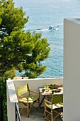 Regiestühle mit grünem Bezug auf Terrasse eines Wohnhauses mit Blick auf Meer und vorbeifahrendem Boot
