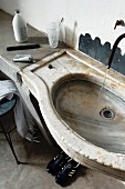 Concrete washstand with integrated, antique stone basin and minimalist outlet pipe