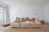 Lots of orange, decorative pillows and three beds lined up in a row with earth tone bedding
