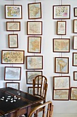 Pictures hung in vertical rows on wires and traditional wooden table and dark wood chairs