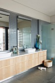 Waschtischzeile mit zwei Waschbecken und Holz Unterschrank in modernem Bad mit grauen Natursteinfliesen