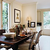 Dunkler Esstisch mit Metallstühlen und Rattangeflecht in offenem Wohnraum im klassizistischen Stil