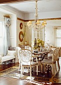 Vintage-style dining room - chairs with latticed backs around set table below chandelier with fabric lampshades