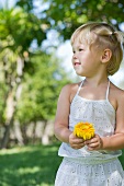 Blondes Mädchen mit einer Blume im Garten