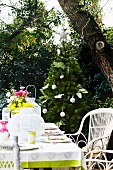 Set terrace table with colourful bouquet and white lantern; decorated Christmas tree in background