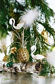 Swan ornaments and baubles hanging from fir branch