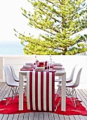 Set table on balcony with red and white striped wallpaper as table runner