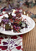 Teller mit Kranz aus Callicarpa, Mini-Hagebutten und lila Efeu und kleinen Kerzen