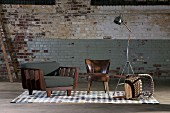 Armchairs, tipped over wooden chair and retro standard lamp against old brick wall