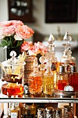 Perfume bottles, room fragrance diffuser and vases of roses on glass table top