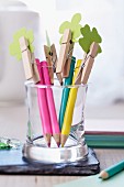 Coloured pencils topped with clothes pegs holding paper shamrock leaves