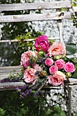 Strauss mit prallen Rosenblüten auf altem Gartenstuhl