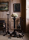 Nostaslgic room with paneled wall, wooden chair, carved wooden pedestals, flowers, wooden tables and old paintings