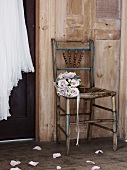 Bouquet of roses on an old chair in front of a wooden wall, wedding dress hanging from a wooden door