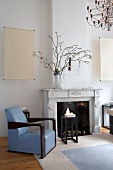 Art Deco interior with open fireplace, elegant armchair with pale blue leather upholstery and dark wood side table