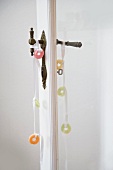 Sweeties tied on decorative ribbons on pair of vintage door handles on door with glass panel