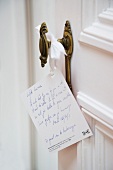 Card with hand-written greeting hanging on vintage interior doorknob