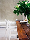 White chair at wooden table with vase of flowers