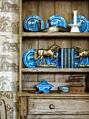 Miniature horse statues in brass and blue and white crockery on dresser shelving