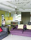 Open-plan, modern interior with strong accents of colour in living and kitchen areas; child in front of fridge