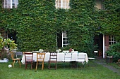 Set table in front of an house facade covered with wild grapevines