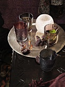 Tray with dried dates, glasses and tea light holders on a dark table