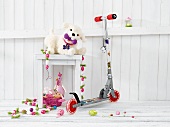 A child's scooter next to a stool with a stuffed animal and Easter decorations
