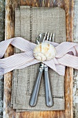 Linen serviette with bow, cutlery and snail shell