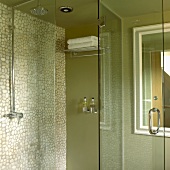Green shower stall with mosaic tile wall and glass door