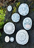Pebbles decorated with various lace doilies on mossy tree trunk