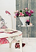 Bouquet of roses in conical vase on small plexiglass table next to chair upholstered in fabric with fifties pattern