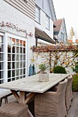 Wicker chairs and rustic wooden table on terrace with lattice terrace windows