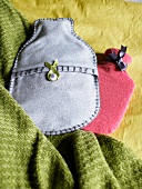 Hot water bottles with handmade covers made from vintage fabric on a green wool blanket