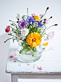 Wildflower bouquet in a water glass on a wooden table