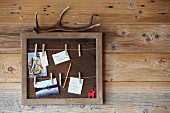 Small, hand-crafted pin board with cards and clothes pegs on cords and antler resting on top