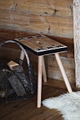 Stool with black decorative crosses and wire basket of firewood