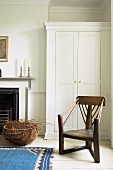 Antique wooden chair in front of white wardrobe next to fireplace in rustic room