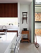 Modern kitchen with contrasting decor, old bistro chair hung on wall & wooden side table
