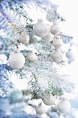 A Christmas tree with artificial snow and white baubles